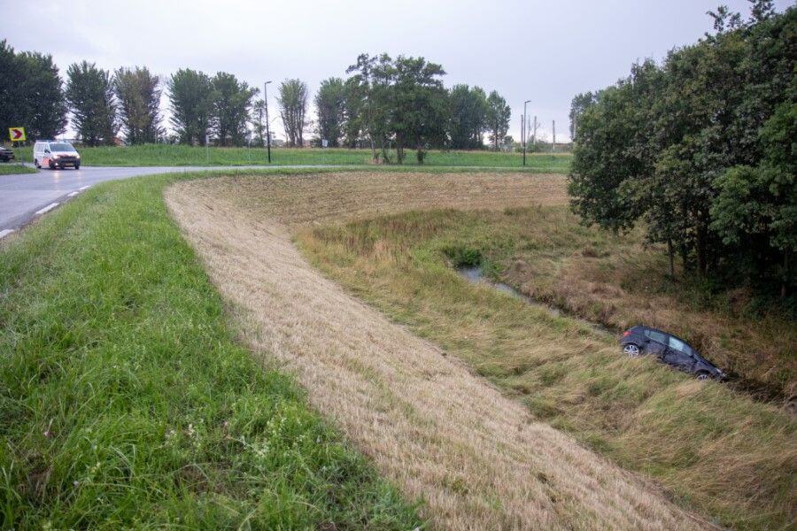 Auto van de dijk af het water in