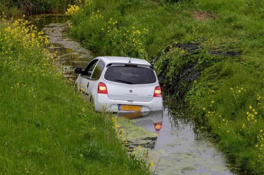 Auto van de dijk af de sloot in