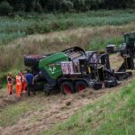 Tractorbestuurder met balenpers van de dijk gereden