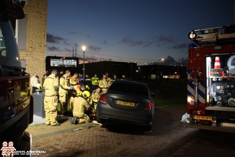 Fietsster bekneld onder auto